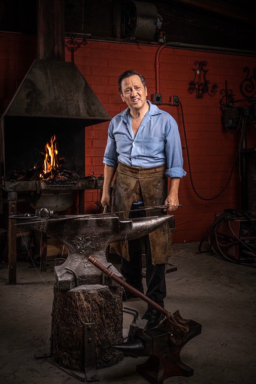 Blacksmith at anvil in workshop with forge fire