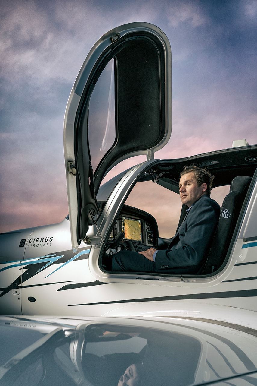 Man in suit seated in Cirrus aircraft cockpit at dusk