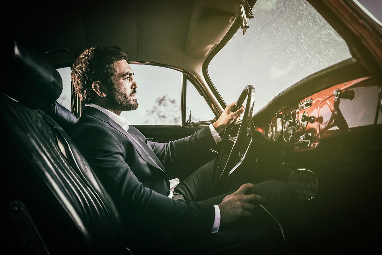 Man in suit driving vintage car interior cinematic portrait