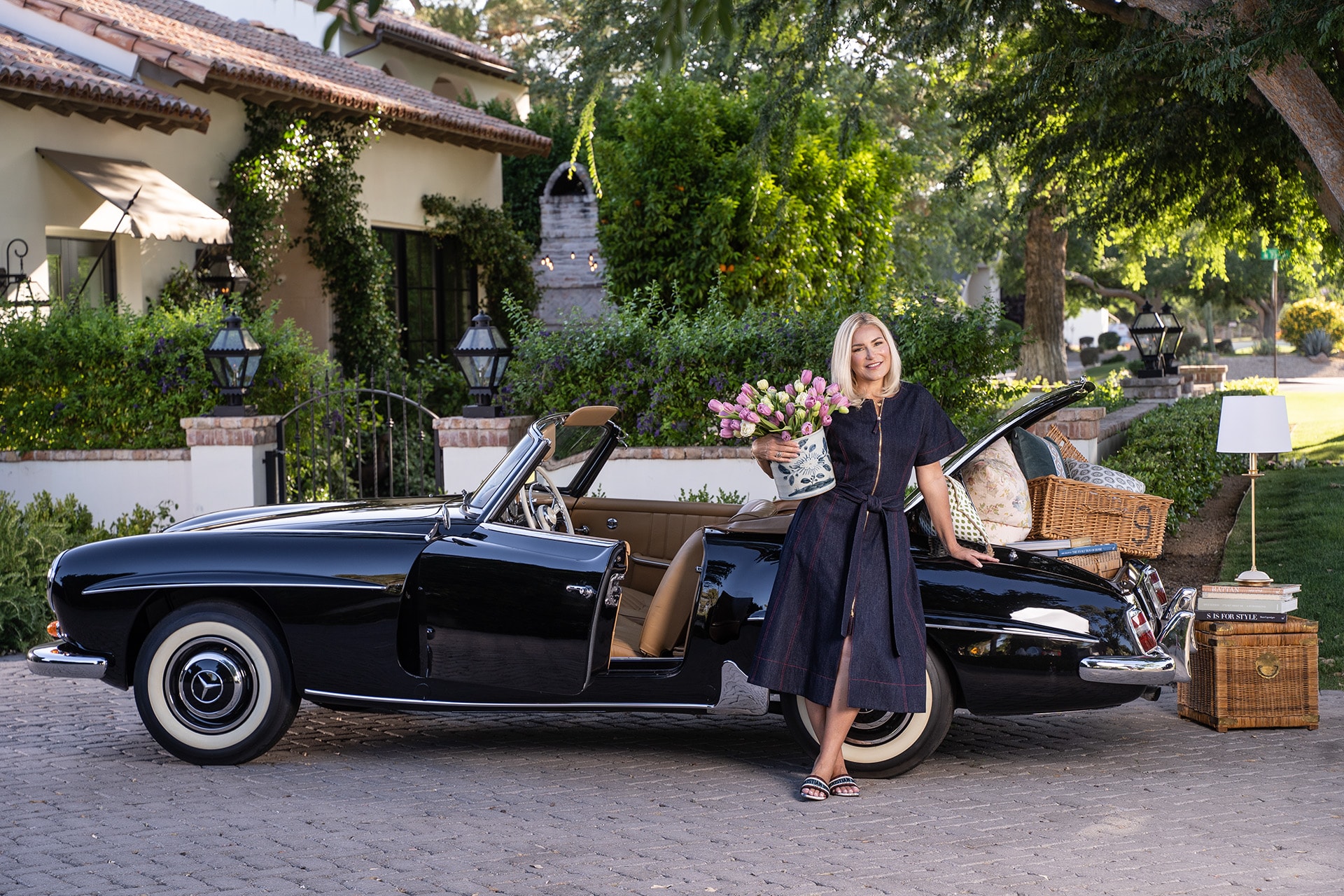 Woman with tulips beside vintage black Mercedes convertible at estate
