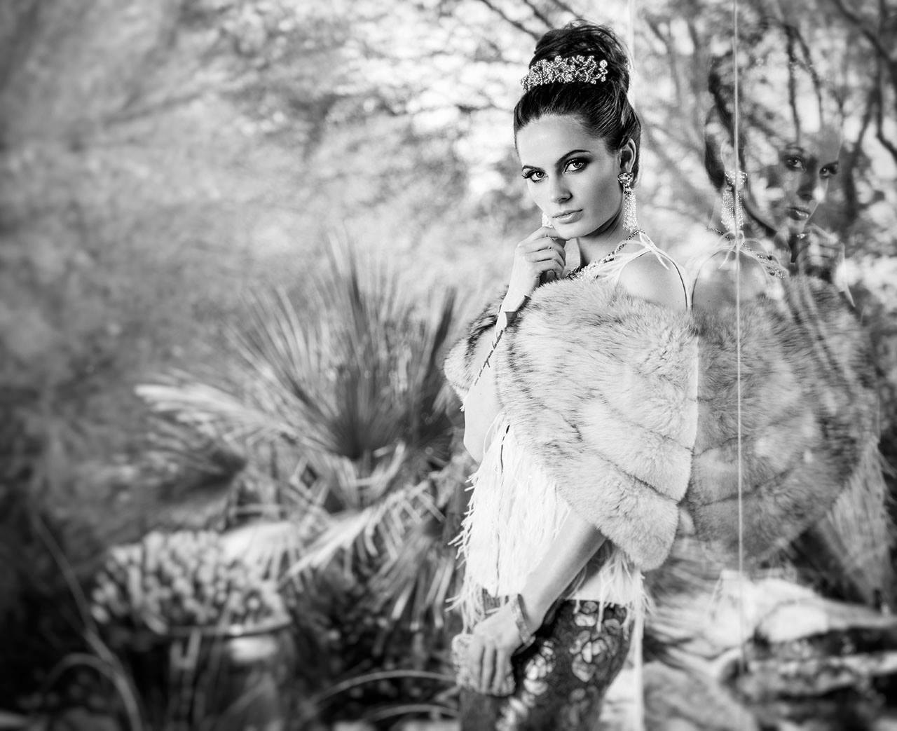 Woman in fur stole and tiara with desert reflection, black and white fashion portrait